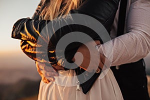 Beautiful wedding couple standing on the top of the mountain in sunset light