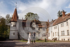 Beautiful wedding couple are walking near old castle, ancient restored architecture, old building, old house outside, vintage