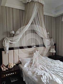 Beautiful wedding dress of the bride lies on the bed in the room