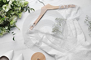 Beautiful wedding dress, engagement ring and flowers on white wooden background, flat lay