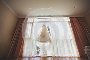 Beautiful wedding dress hanging in the bride`s room