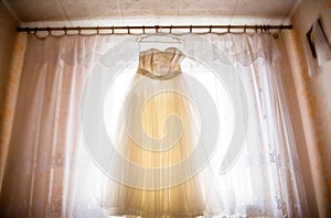 Beautiful wedding dress hanging in the bride`s room.