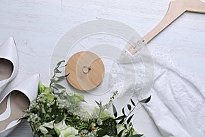 Beautiful wedding dress, shoes, engagement ring and flowers on wooden background, flat lay