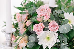 Beautiful wedding floral decoration on a table in a restaurant. White tablecloths, bright room, candles, close-up shooting. The ev