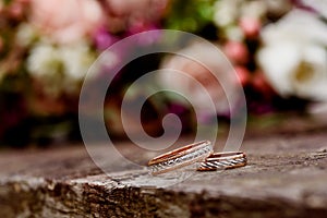 Beautiful wedding rings on a dark wooden background on a background of flowers.