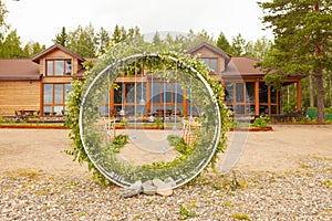 Beautiful wedding set up. Area of the wedding ceremony. Round arch, brown chairs decorated with flowers, greenery. Cute, trendy