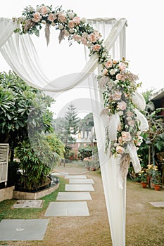 Beautiful wedding venue with a white arch decorated with lush green foliage and vibrant blooms