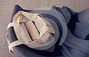 Beautiful weighty books in colored fabric covers in an open bag made of natural linen, next to it lies a gray cozy shawl.