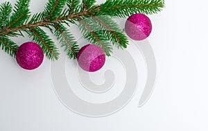 A beautiful white background on which lies a branch of a Christmas tree with New Year`s purple balls. Place for text and