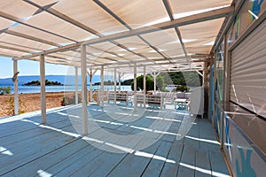 Beautiful white-blue wooden restaurant standing on a sandy beach in the background of the sea and a small tree