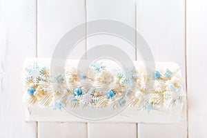 Beautiful white cake roll in front of a white background. The cake has snowflake-shaped confectionery decorations