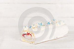 Beautiful white cake roll in front of a white background. The cake has snowflake-shaped confectionery decorations