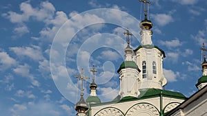 beautiful white clouds float on the blue sky above the domes of an Orthodox cathedral with golden domes and crosses.