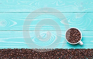 Beautiful white coffee cup with coffee beans on turquoise wooden background