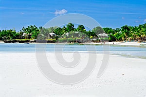 Beautiful white coral sand beach with palms and cottages, turquoise blue ocean