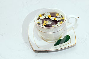 A beautiful white cup with a gold border decorated with flowers, herbal green healthy tea. Business account design.