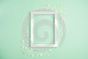 Beautiful white flowers and photo frame on pastel mint background