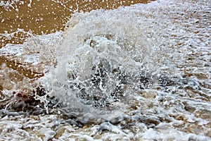 Sea water surface with foam and ripples close up as background.