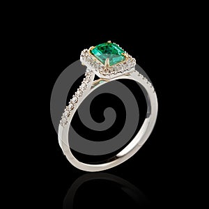 Beautiful white gold ring with diamonds and emerald on a black background