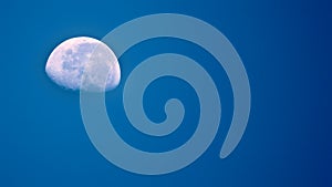 Beautiful white half moon in a uniform blue background shining with white glow
