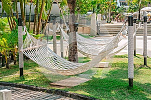 Beautiful white hammocks hanging on open air under trees in tropical hotel, side view