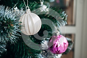 Beautiful white matte ball on artificial Christmas tree. Selective focus. Holiday card with decorations for the New Year`s Eve