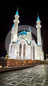 Beautiful white mosque with minarets against a dark cloudy sky in night or evening. Ramadan Holiday