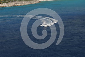 Beautiful white pleasure boat with driver leaving a wide wake in the sea