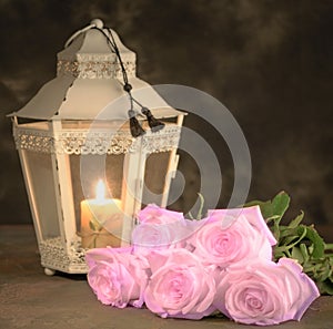 Beautiful white roses and candle on table against black background