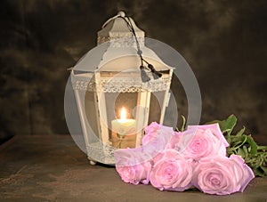 Beautiful white roses and candle on table against black background