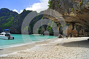 Beautiful white sandy beach beside the blue ocean surrounded by the treed rocks. Thailand.