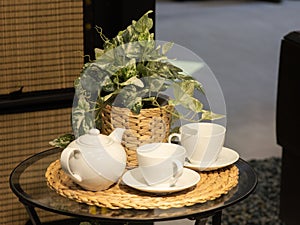 A beautiful white set of two bowls and a teapot, in the background a flower