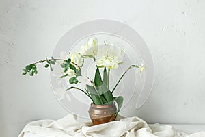 Beautiful white tulips and daffodils on wooden table against rustic wall. Happy Mothers day. Stylish simple spring bouquet in