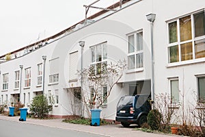 Beautiful white two-storey house with bushes and garbage cans and parked car. Germany.