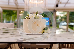 Beautiful white wedding or birthday cake with roses flowers on marble table, restaurant background