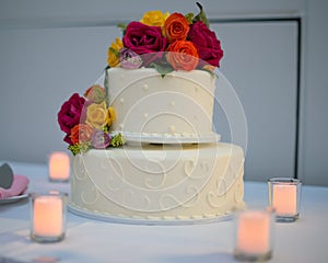 Beautiful white wedding cake with real flowers surrounded by candles