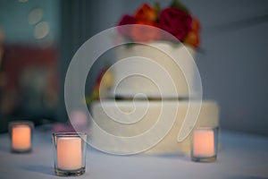 Beautiful white wedding cake with real flowers surrounded by candles