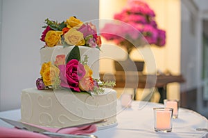 Beautiful white wedding cake with real flowers surrounded by candles