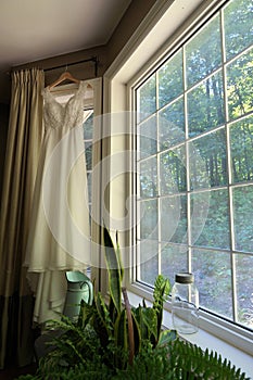 Beautiful White Wedding Dress Hanging in Window of Country House