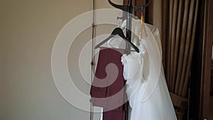 Beautiful white wedding dress hangs on a hanger on the wardrobe in the bedroom.