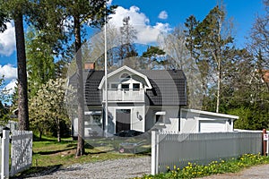 Beautiful white wooden house two floors. Villa cottage in the countryside with white fence. Garden landscape design. Gardening