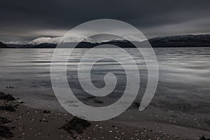 Beautiful wide shot of glaciers by the body of water under a gray sky