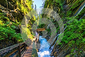 Beautiful Wimbachklamm gorge with wooden path in autumn colors, Ramsau bei Berchtesgaden in Germany. Waterfall at Wimbachklamm