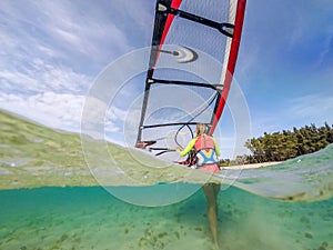 Beautiful windsurfer girl with a board on a tropical beach, makes water start, view from the waterline
