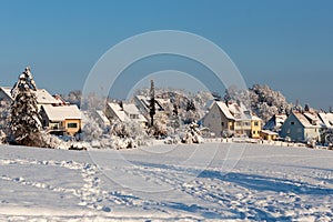 Beautiful winter in a European village - view of a snow-covered field against the backdrop of country houses