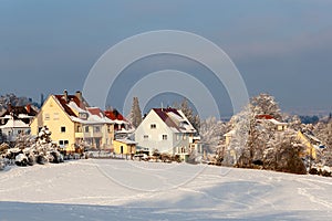 Beautiful winter in a European village - view of a snow-covered field against the backdrop of country houses