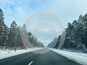 Beautiful winter landscape with asphalt road,forest and blue sky. frozen wintry day and path drive