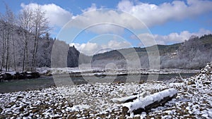 beautiful winter landscape with a calm river flowing around a snow-covered shore. Frosty trees in a snowy forest on a
