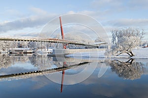 Beautiful winter landscape with footbridge and nice reflection in water of river