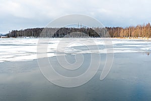 Beautiful winter landscape forest on the lake shore on a sunny frosty day. Panorama of the coastline covered with snow and birch